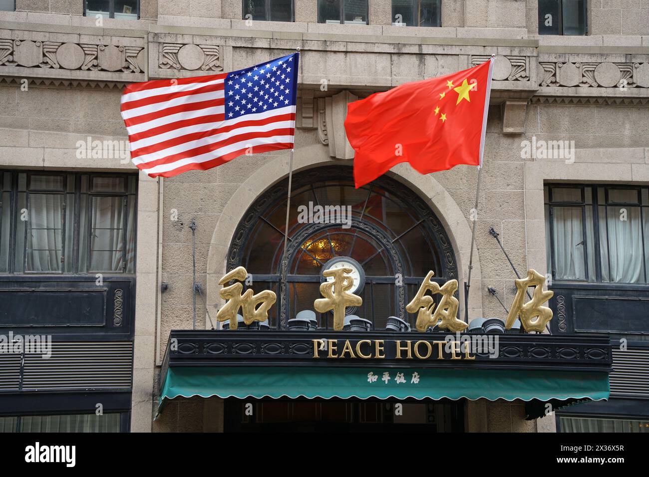 SHANGHAI, CHINE - 25 AVRIL 2024 - le drapeau rouge cinq étoiles de la Chine et le drapeau américain sont accrochés au-dessus de l'entrée de l'hôtel Peace le long de la route de Nanjing Pede Banque D'Images
