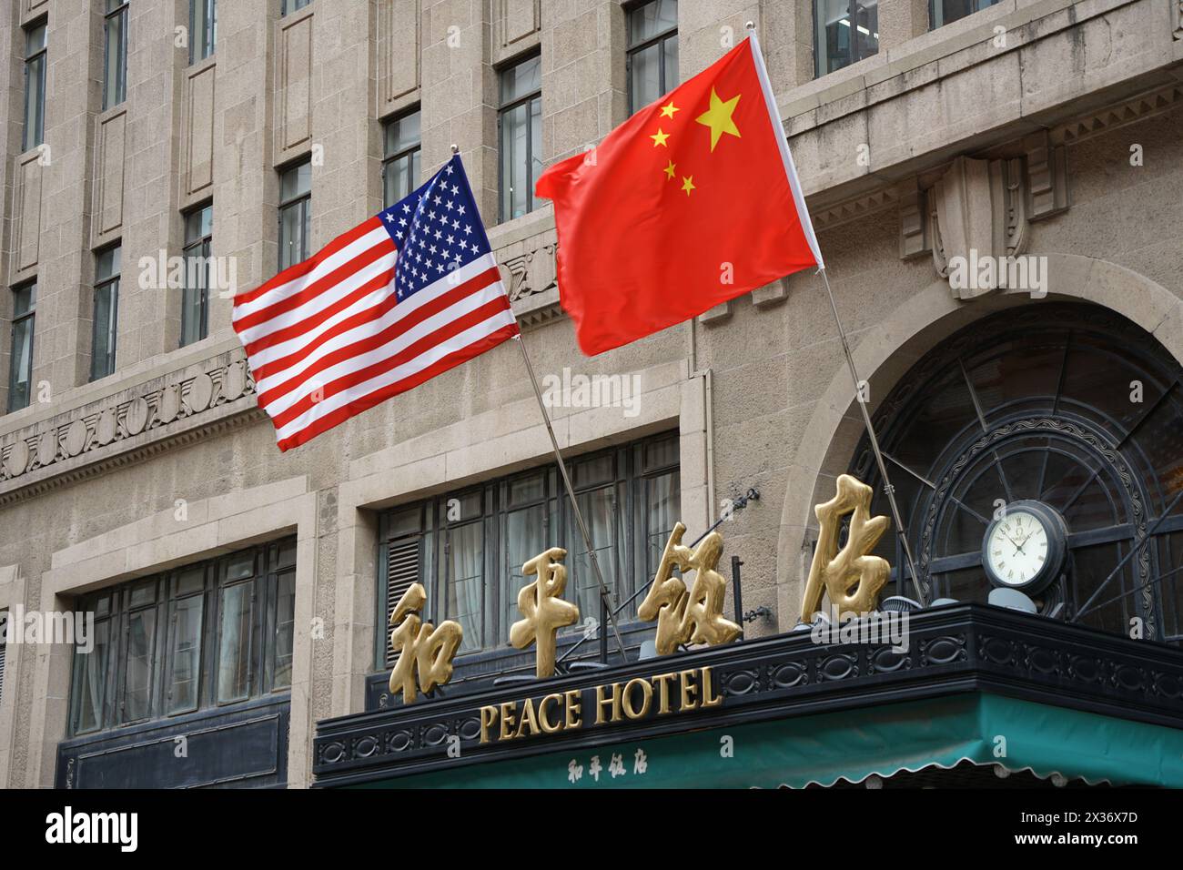 SHANGHAI, CHINE - 25 AVRIL 2024 - le drapeau rouge cinq étoiles de la Chine et le drapeau américain sont accrochés au-dessus de l'entrée de l'hôtel Peace le long de la route de Nanjing Pede Banque D'Images