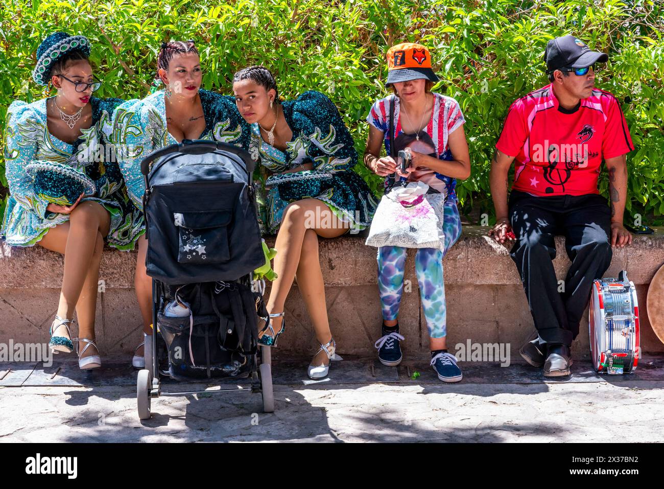 Jeunes assis à l'ombre de la place pendant Une pause à la Fiesta de la Virgen de la Candelaria, San Pedro de Atacama, Chili. Banque D'Images