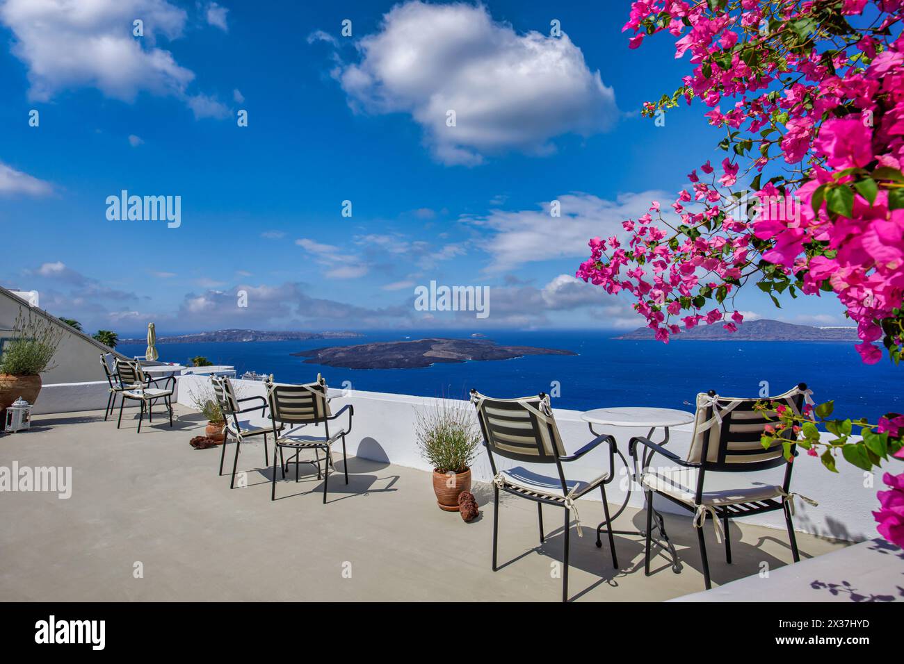 Romantique couple extérieur tables en marbre blanc chaises sur terrasse avec des fleurs donnant sur la mer, Oia Village, Santorin, Cyclades, Grèce. Vacances d'été, Banque D'Images