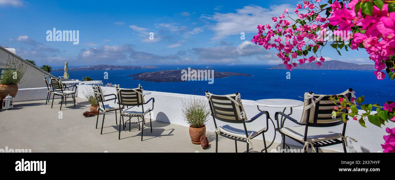 Romantique couple extérieur tables en marbre blanc chaises sur terrasse avec des fleurs donnant sur la mer, Oia Village, Santorin, Cyclades, Grèce. Vacances d'été, Banque D'Images