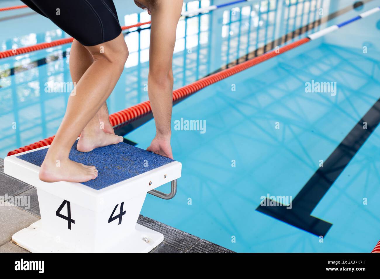 Jeune nageur caucasien se préparant à plonger dans une piscine intérieure Banque D'Images