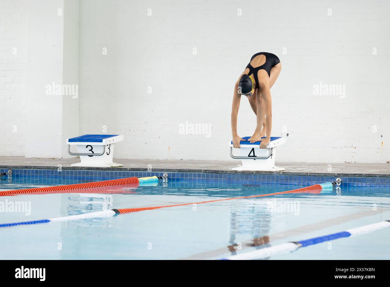 Biracial jeune femme nageuse se préparant à plonger dans la piscine intérieure, copier l'espace Banque D'Images