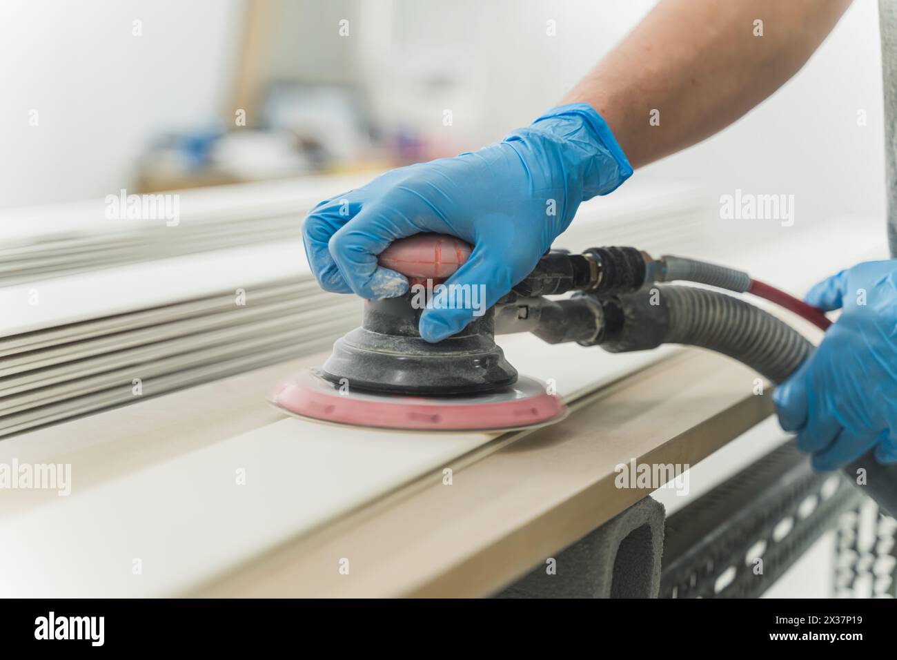 gros plan des mains du travailleur avec des gants en utilisant une ponceuse électrique dans l'atelier. Menuisier ponçant la planche en bois sur la table. Travaux de charpenterie. Photo de haute qualité Banque D'Images