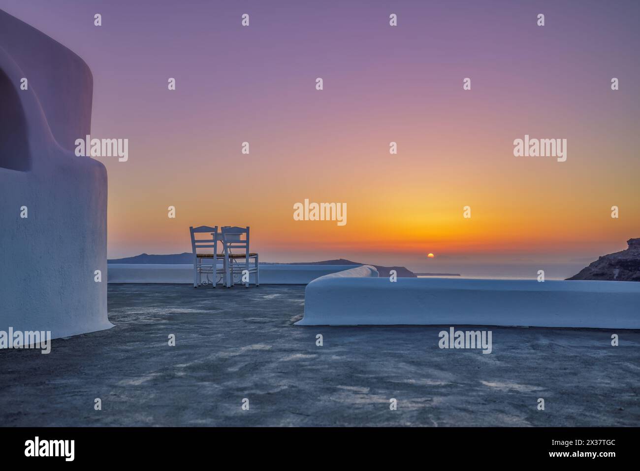 Terrasse avec deux chaises et vue sur la mer au coucher du soleil. Île de Santorin, Grèce. Voyage et vacances arrière-plan. Meilleur dans le paysage de voyage pour couple d'amour romantique Banque D'Images