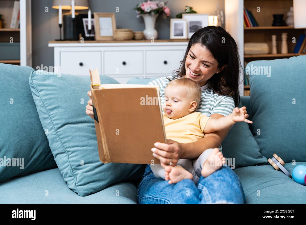 Jeune mère heureuse lisant un livre de conte de fées à son bébé. Maman et enfant assis sur le canapé à la maison profitant de l'imagination. Vie parent et enfant Banque D'Images