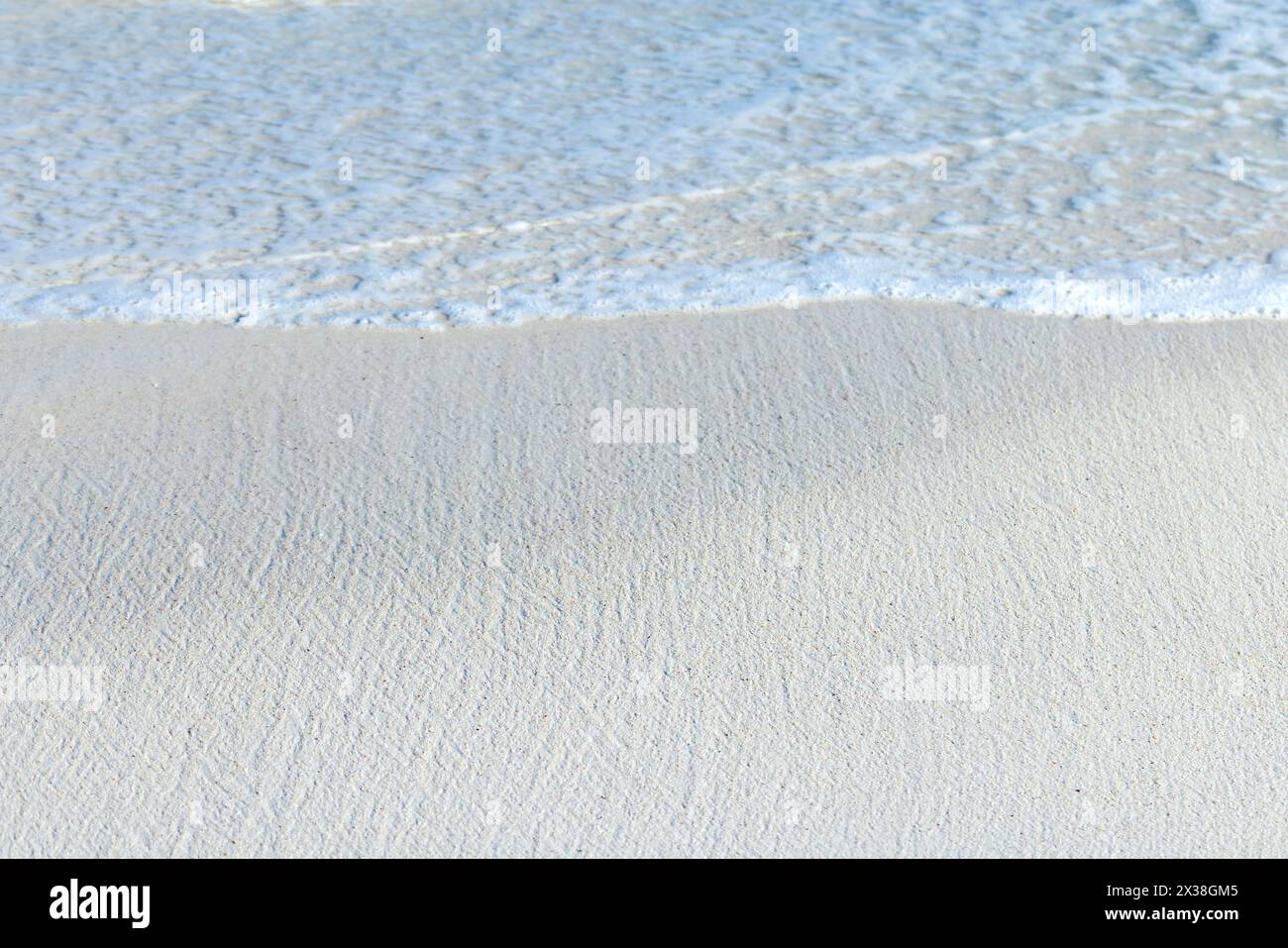 Sable blanc et eau du rivage. Photo de fond naturelle avec mise au point sélective Banque D'Images