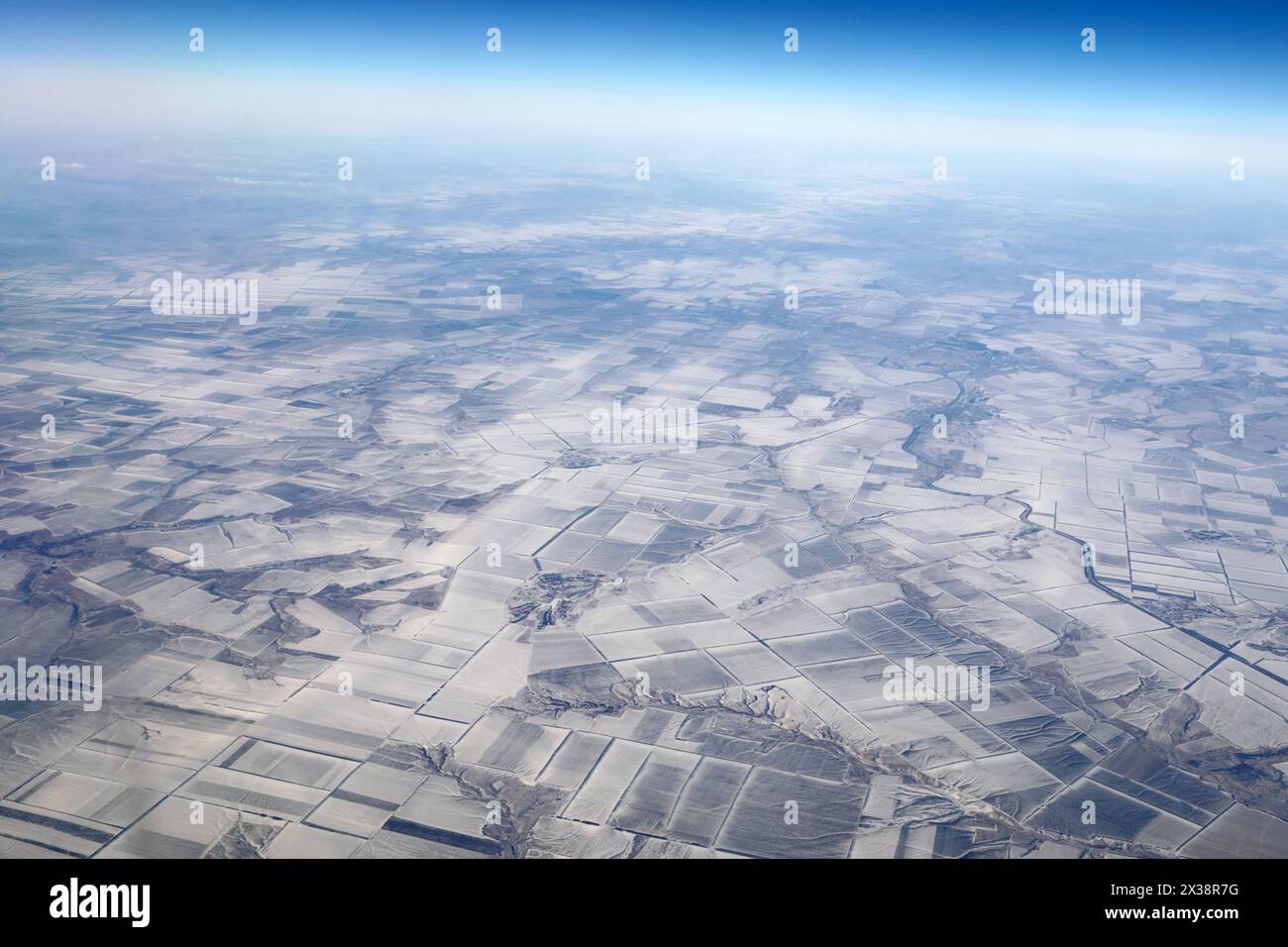 Plaines enneigées et rivières en hiver, vue depuis la fenêtre de l'avion volant Banque D'Images
