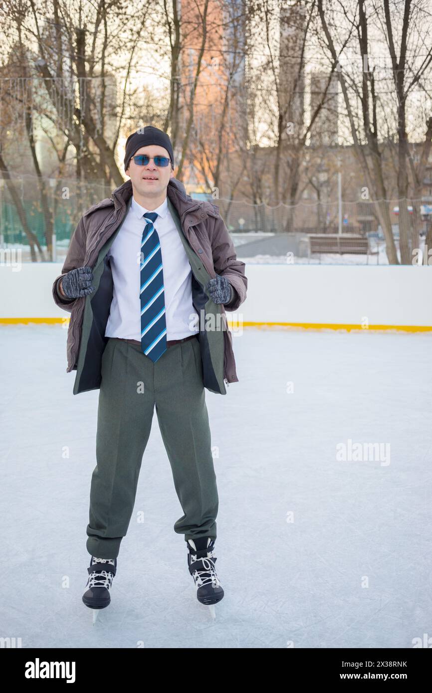 Homme en costume et lunettes se tient sur la patinoire à la journée ensoleillée d'hiver Banque D'Images