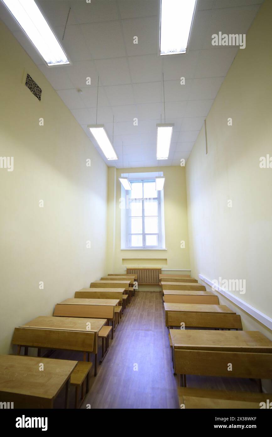 Vide petite salle de classe avec des tables en bois pour les étudiants et fenêtre Banque D'Images