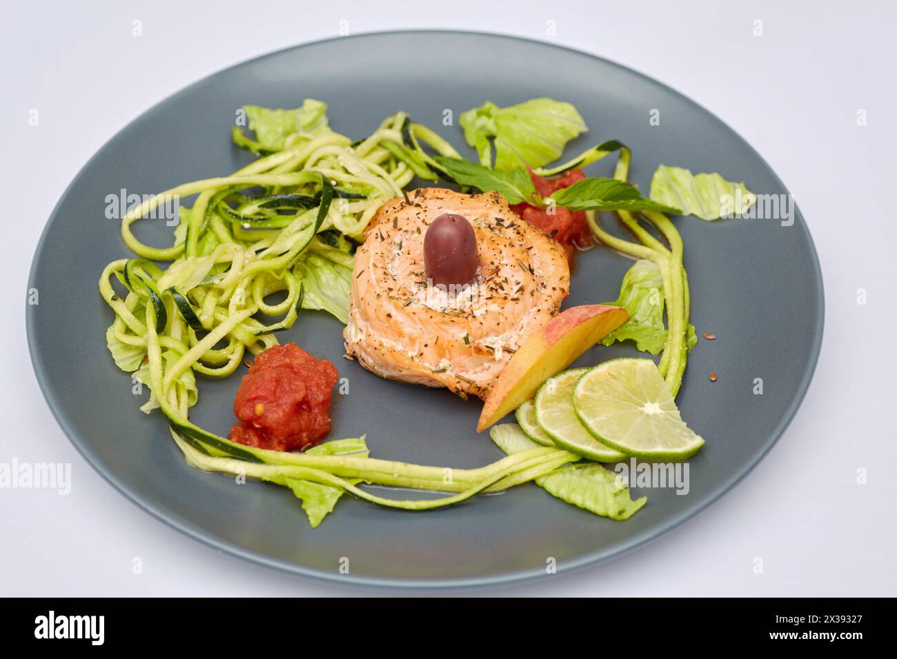 Rouleau de poisson rouge avec légumes et fruits râpés et tranchés sur l'assiette. Banque D'Images