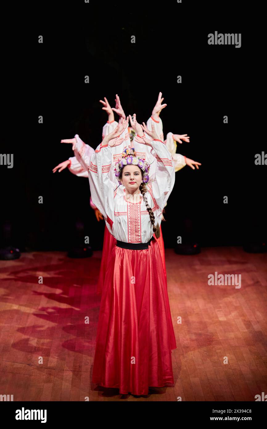 Des filles en jupes rouges, des chemisiers blancs brodés et avec des couronnes sur la tête dansent la danse folklorique russe pendant le concert Banque D'Images