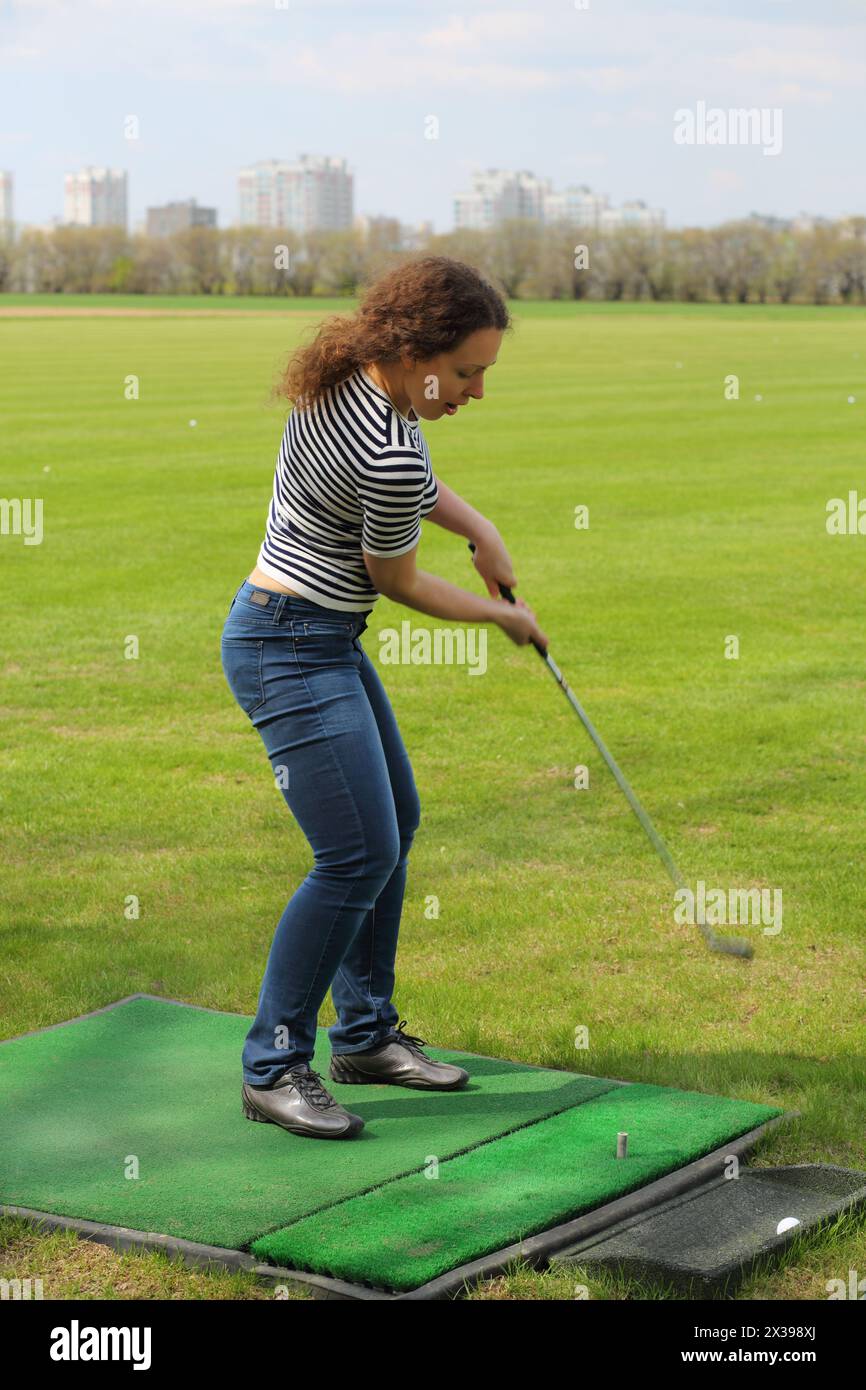 Jeune femme frappe par balle de cammock pour le golf de pelouse artificielle Banque D'Images