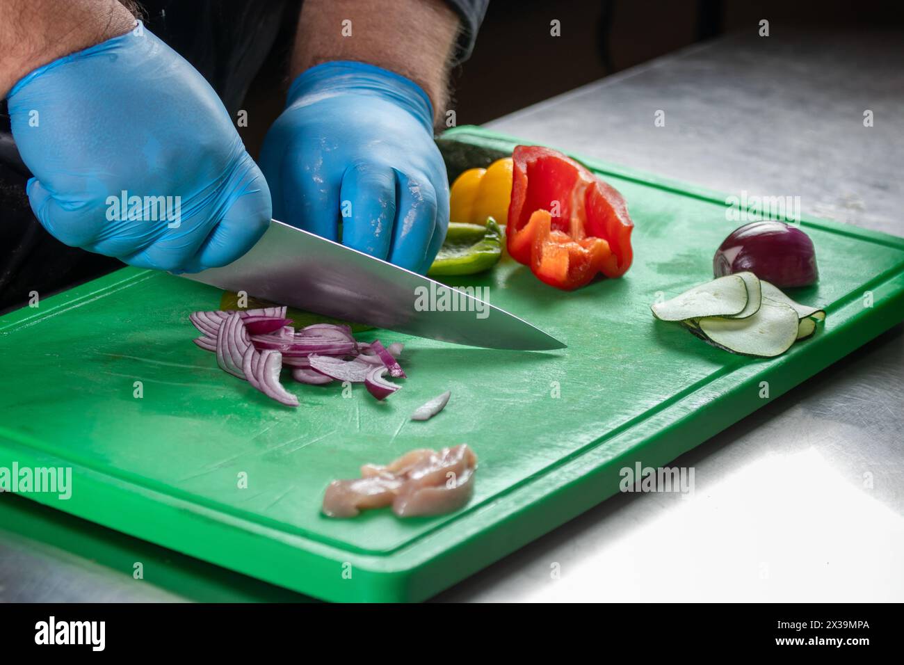 Un chef qualifié prépare méticuleusement des ingrédients frais, y compris la viande, les oignons, les poivrons et les concombres, pour une recette savoureuse, mettant en vedette culinaire ex Banque D'Images