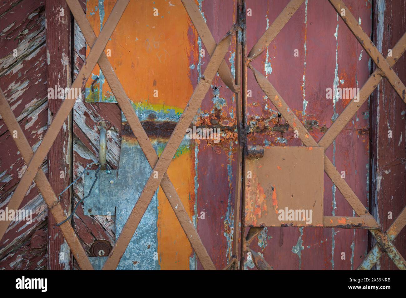 Une photo en gros plan d'une grille métallique et d'un mur en bois et d'une porte en bois gravement altérés avec de la peinture écaillée, dans les ruelles de Cienfuegos, Cuba Banque D'Images