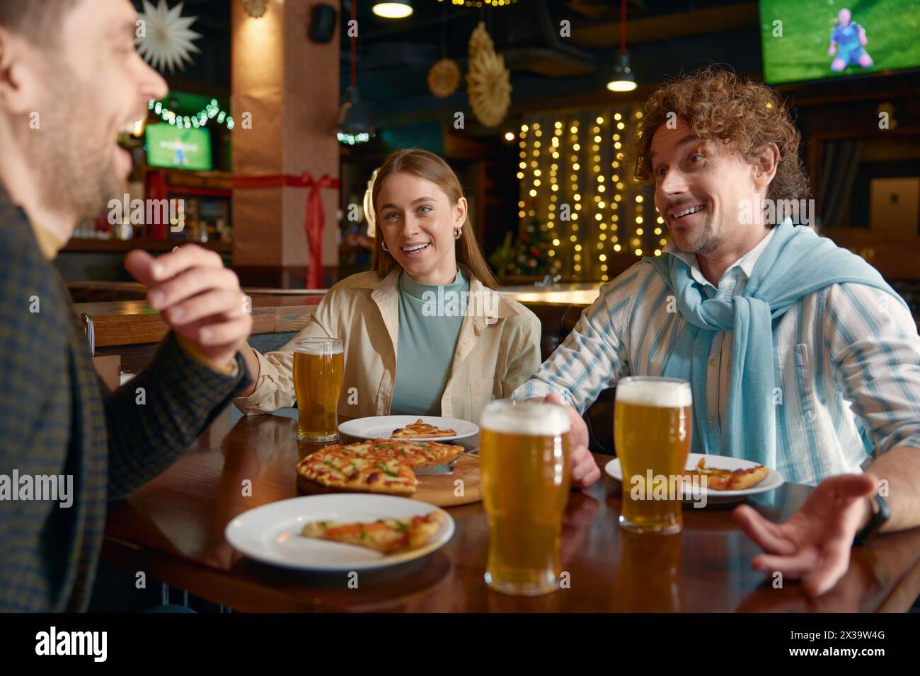 Amis mangeant de la pizza buvant de la bière pendant le repos dans un pub Banque D'Images