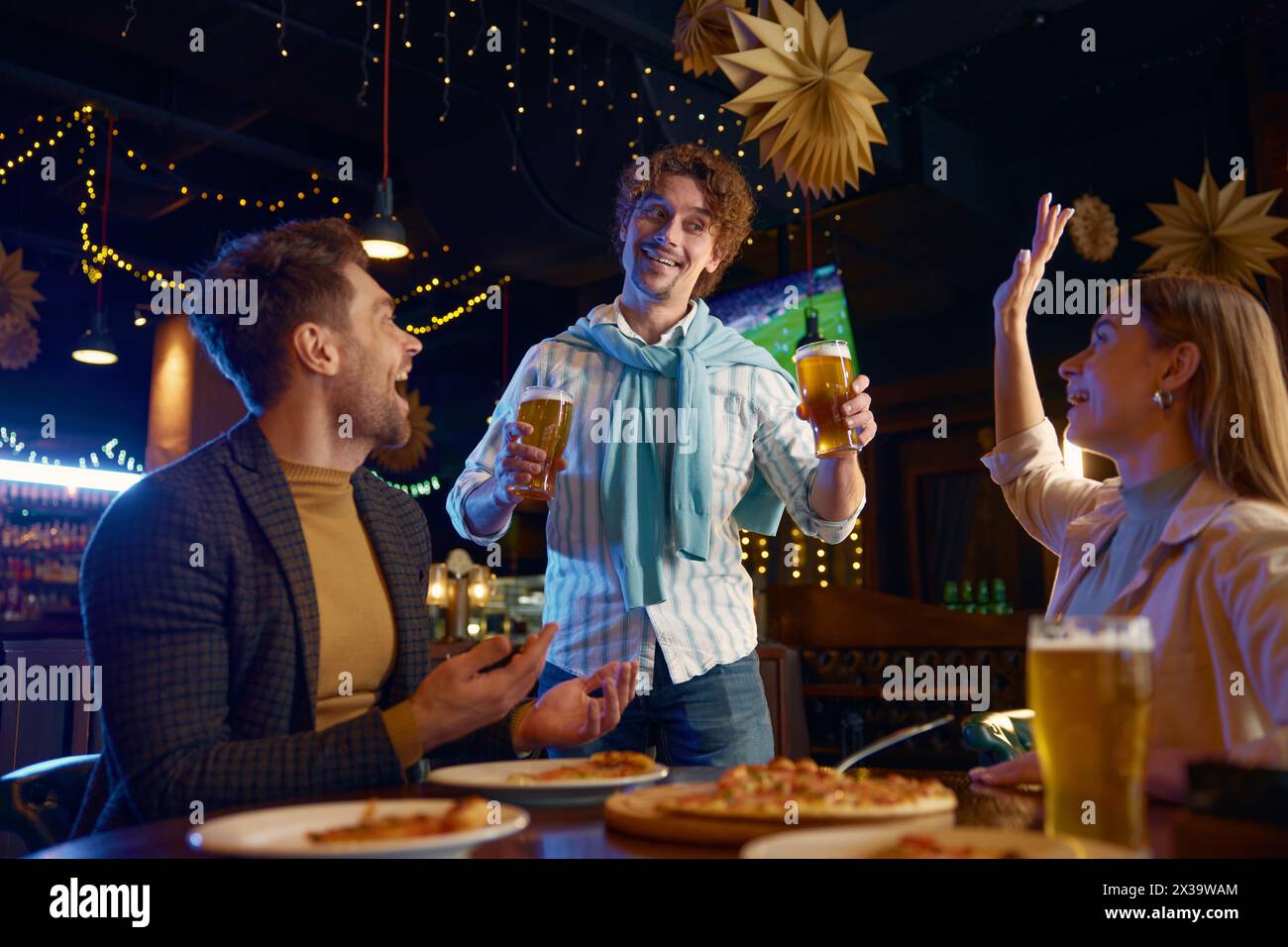 Gars joyeux achetant de la bière d'amis pendant le repos dans le bar Banque D'Images