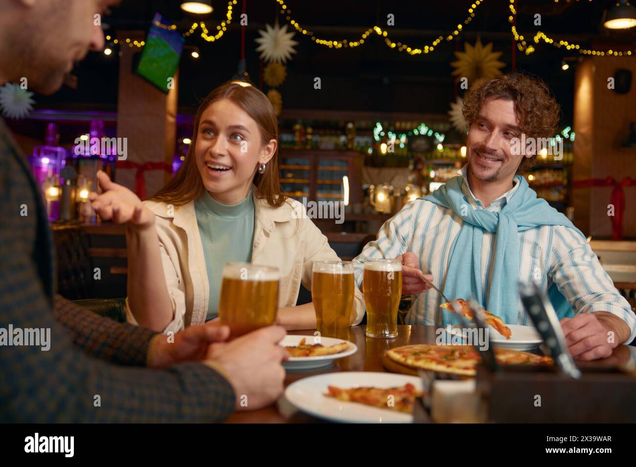 Jeunes amis mangeant de la pizza buvant de la bière pendant le repos dans un pub Banque D'Images