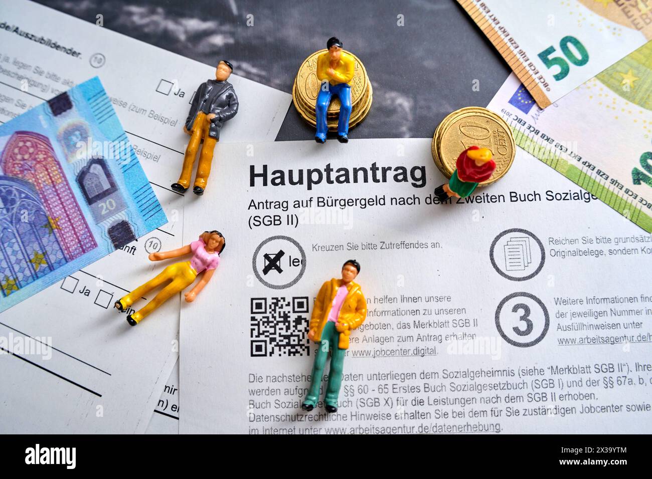 Augsbourg, Bavière, Allemagne - 25 avril 2024 : demande de revenu des citoyens, application principale avec les billets en euros et les chiffres relatifs aux personnes. Concept de protection sociale *** Antrag auf Bürgergeld, Hauptantrag mit Euro Geldscheinen und Menschen Figuren. Sozialhilfe Konzept Banque D'Images