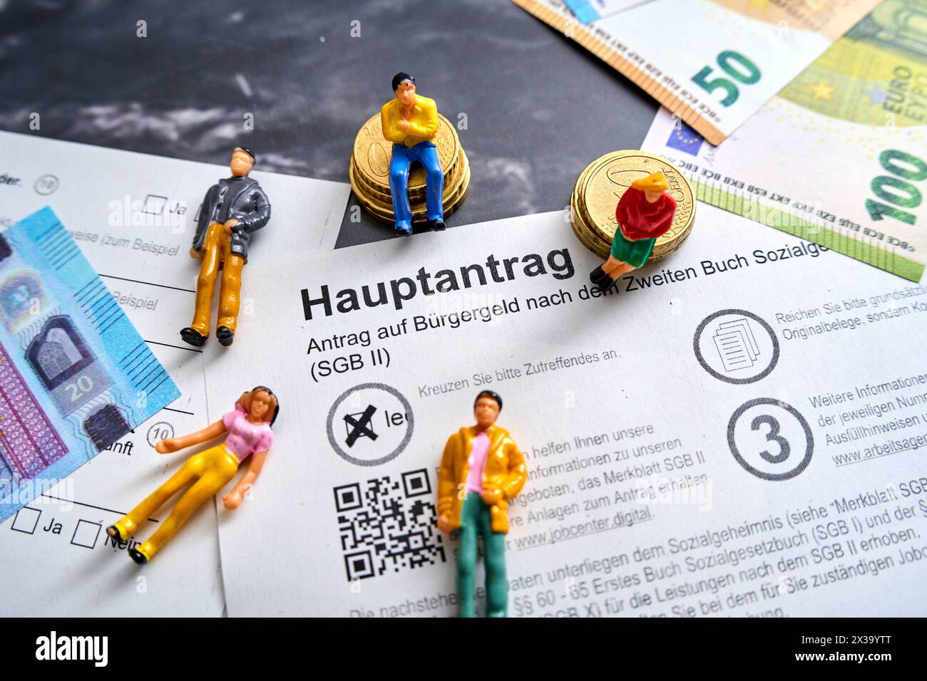 Augsbourg, Bavière, Allemagne - 25 avril 2024 : demande de revenu des citoyens, application principale avec les billets en euros et les chiffres relatifs aux personnes. Concept de protection sociale *** Antrag auf Bürgergeld, Hauptantrag mit Euro Geldscheinen und Menschen Figuren. Sozialhilfe Konzept Banque D'Images