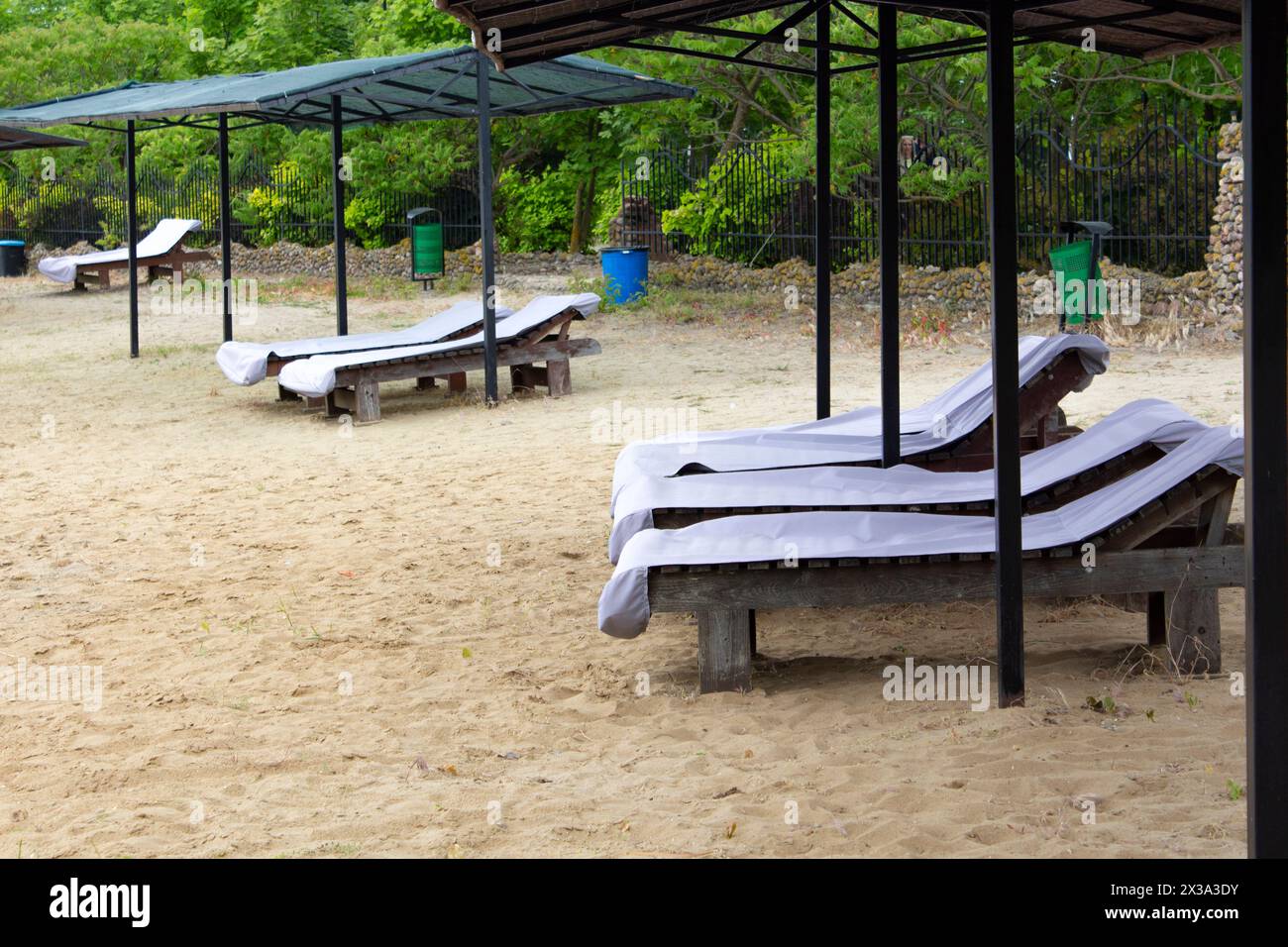 Zone de loisirs de plage sur la rive du lac. Des transats vides se tiennent sur le sable. La plage attend les touristes. Banque D'Images