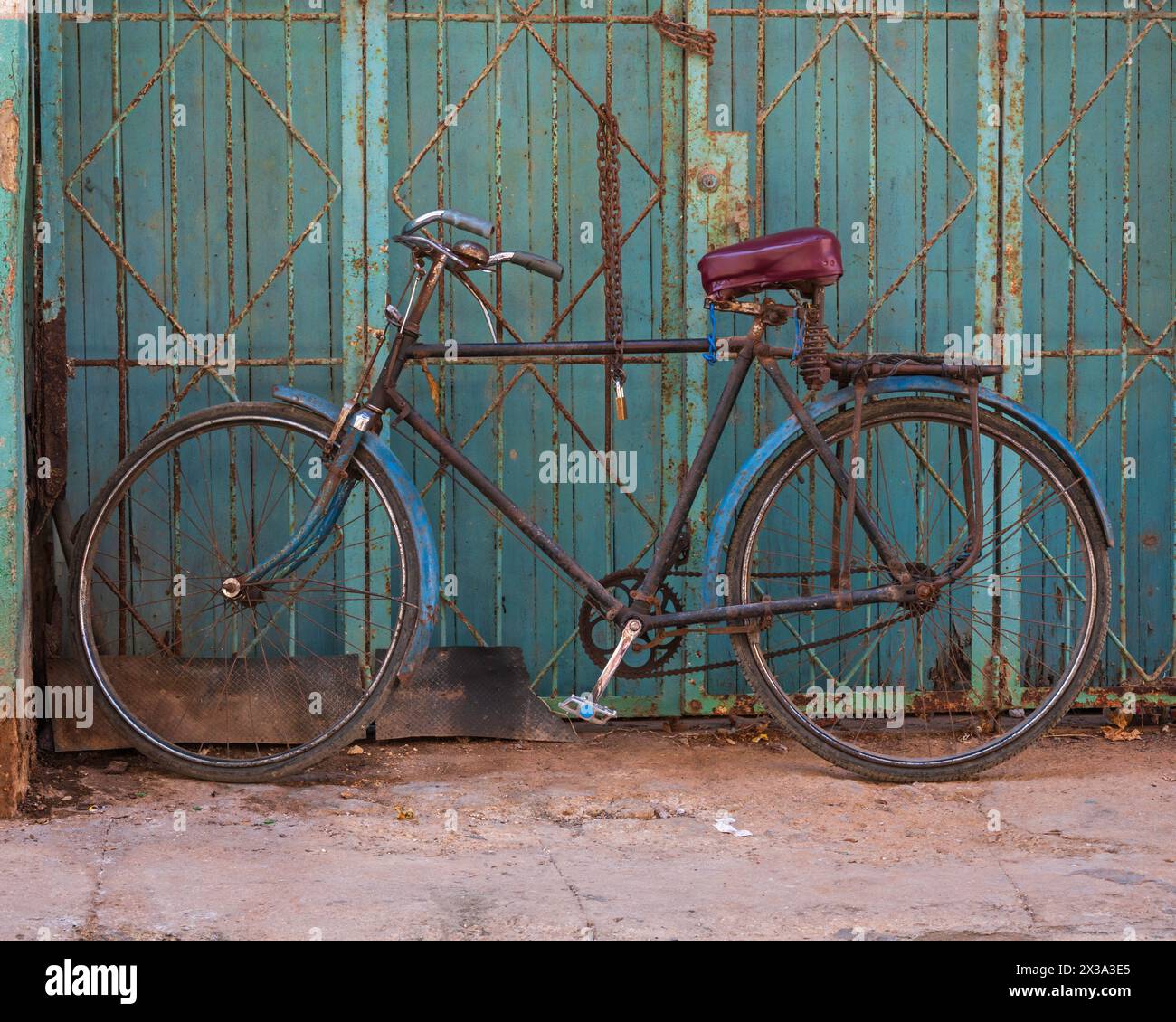 Un vieux vélo rouillé sur un trottoir, penché vers le haut d'une grille métallique dans les rues arrière de la vieille ville, la Havane, Cuba. Banque D'Images