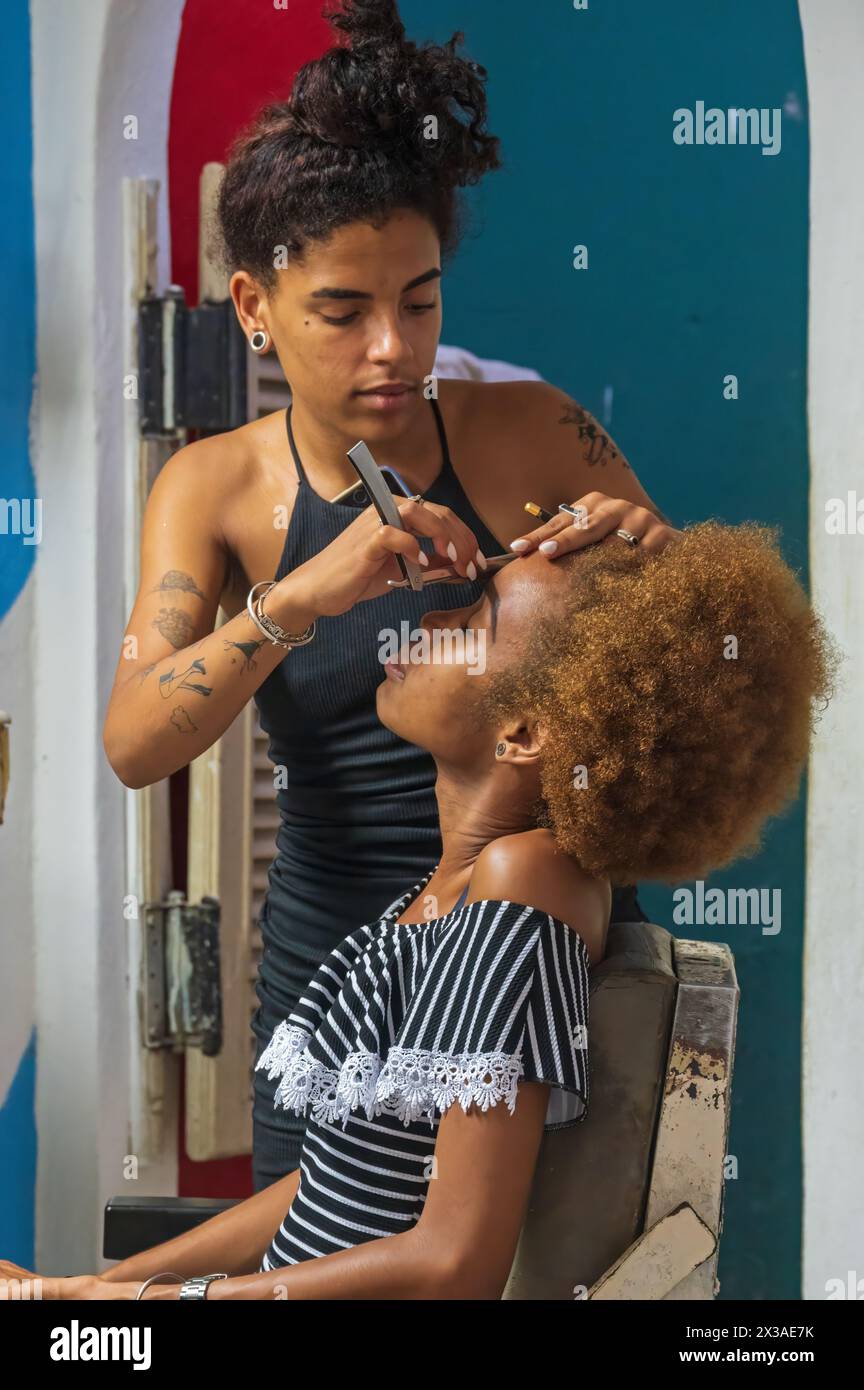 Une jeune femme se faisant coiffer dans un salon de coiffure dans la vieille ville, la Havane, Cuba Banque D'Images