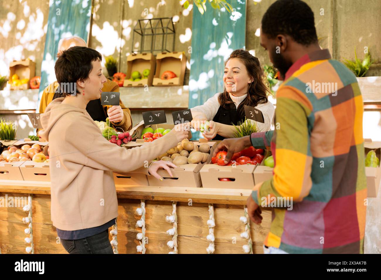 Commerçant amical souriant offrant au client de goûter des variétés de pommes fraîches de saison au marché alimentaire. Heureuse agricultrice vendant des fruits et légumes biologiques locaux. Banque D'Images