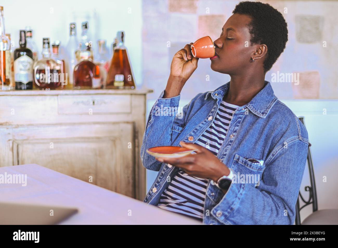 Femme de contenu buvant dans une tasse à espresso dans un cadre de restaurant relaxant Banque D'Images
