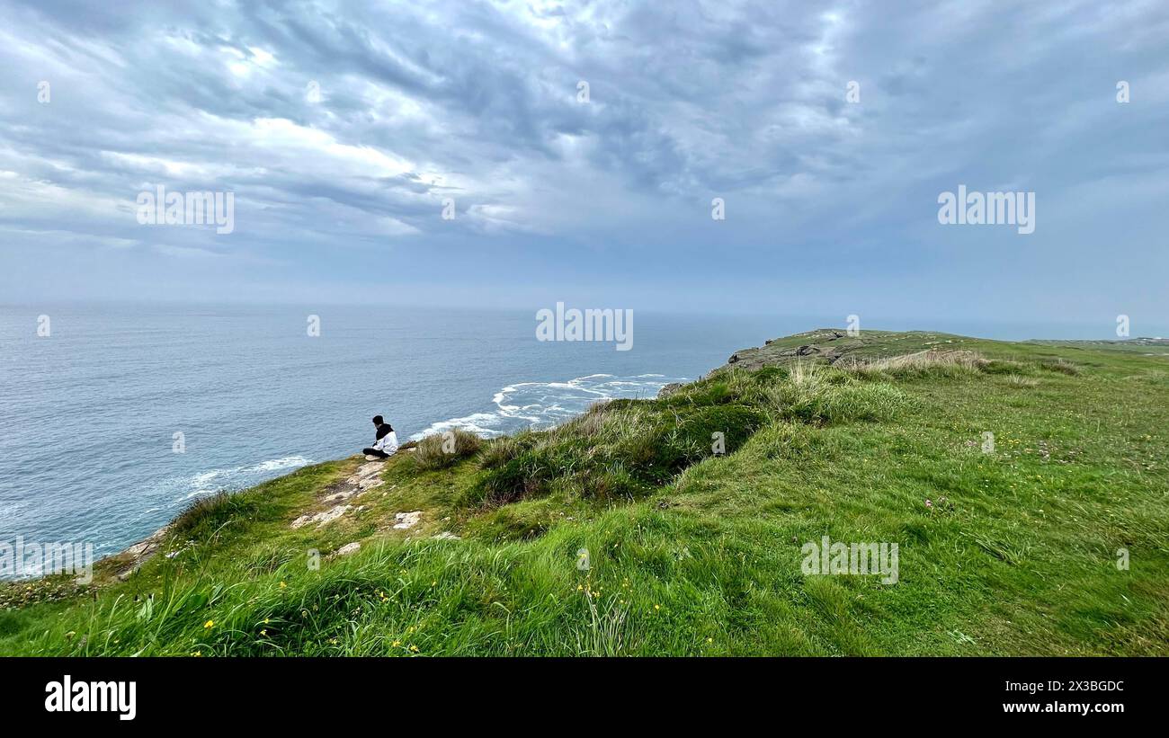 Personne méconnaissable assise observant un jour nuageux la mer de Cabo de Ajo en Cantabrie Espagne Banque D'Images