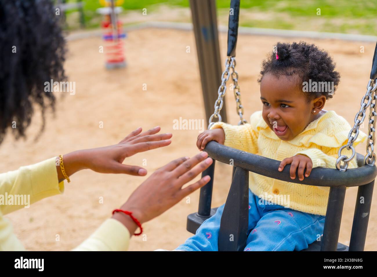 Photo recadrée d'une fille africaine et d'une mère méconnaissable se balançant dans le parc Banque D'Images
