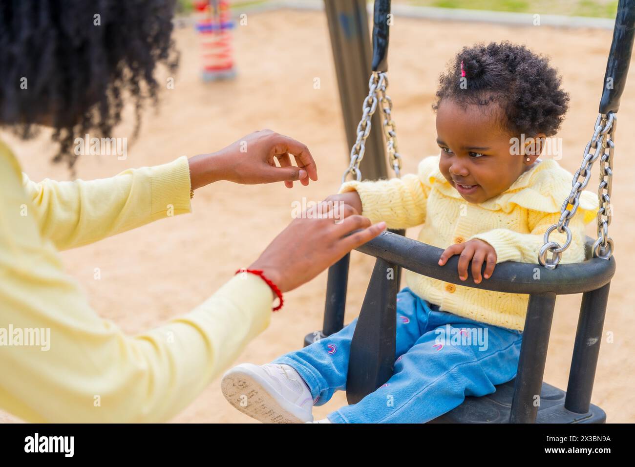 Gros plan d'une heureuse petite fille africaine balançant avec sa mère dans un parc Banque D'Images