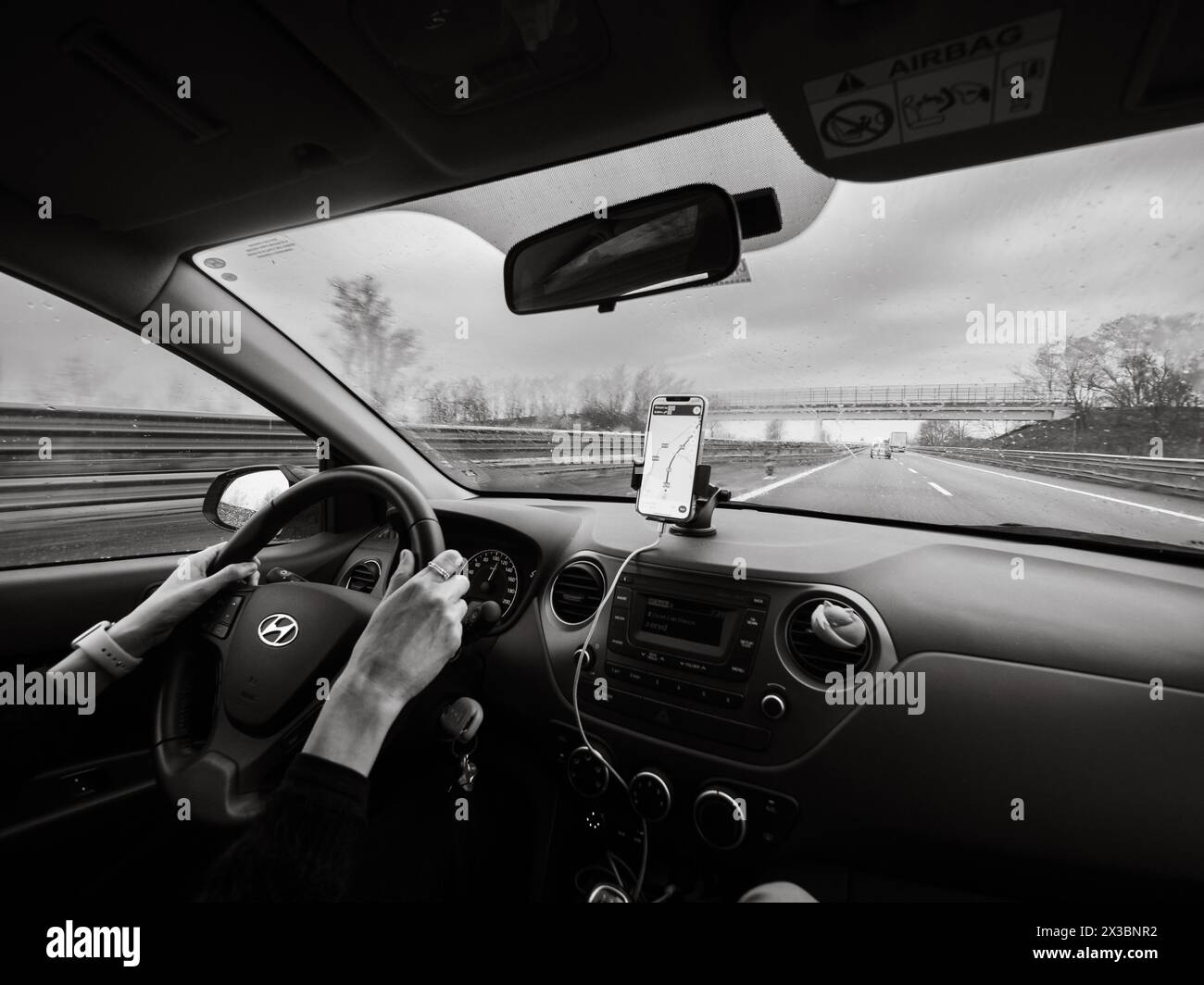 Photo en noir et blanc du point de vue d'un conducteur sur l'autoroute avec un smartphone pour la navigation, autoroute A1 A8 près de Milan, Italie Banque D'Images