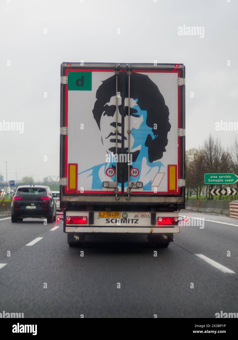 Arrière d'un camion affichant une grande illustration de visage, vu lors de la conduite sur une autoroute A1 A8 près de Milan, Italie Banque D'Images