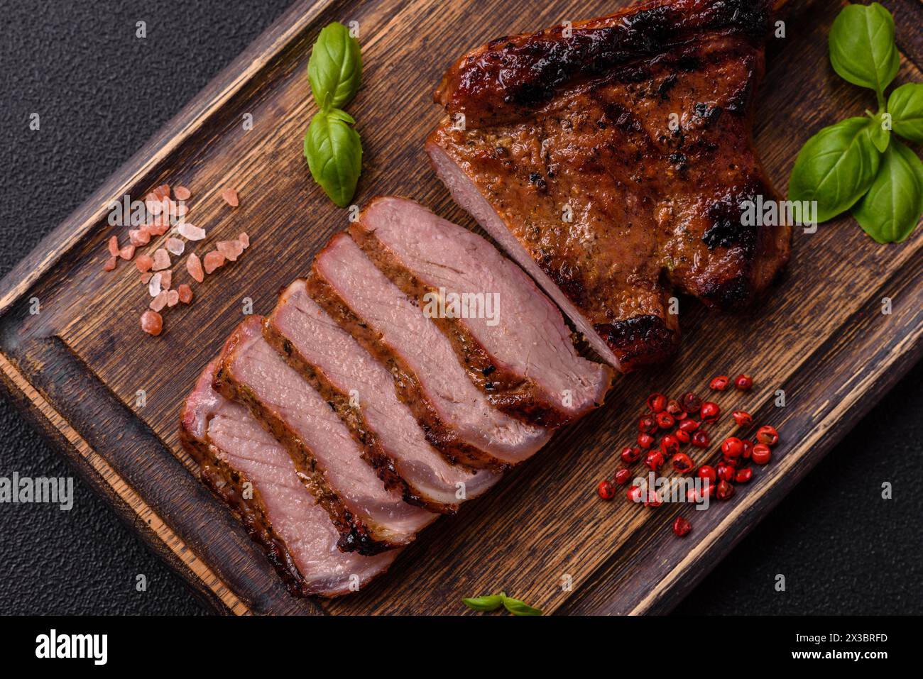 Délicieux steak de bœuf juteux sur l'os, tomahawk avec du sel, des épices et des herbes sur un fond de béton foncé Banque D'Images