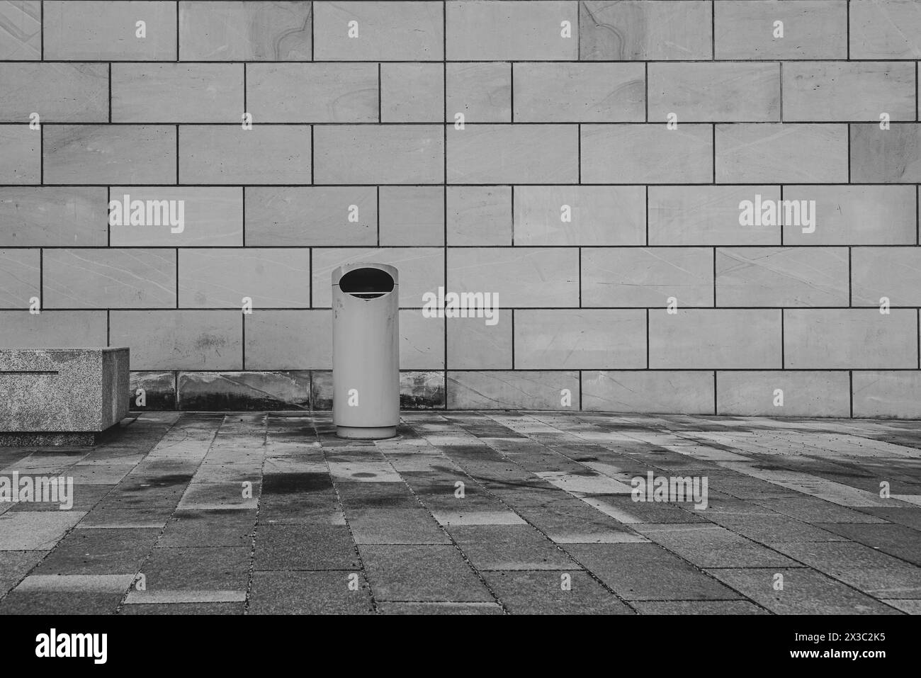 Une poubelle devant une façade en grès, minimaliste, poubelle urbaine, photo noir et blanc Banque D'Images