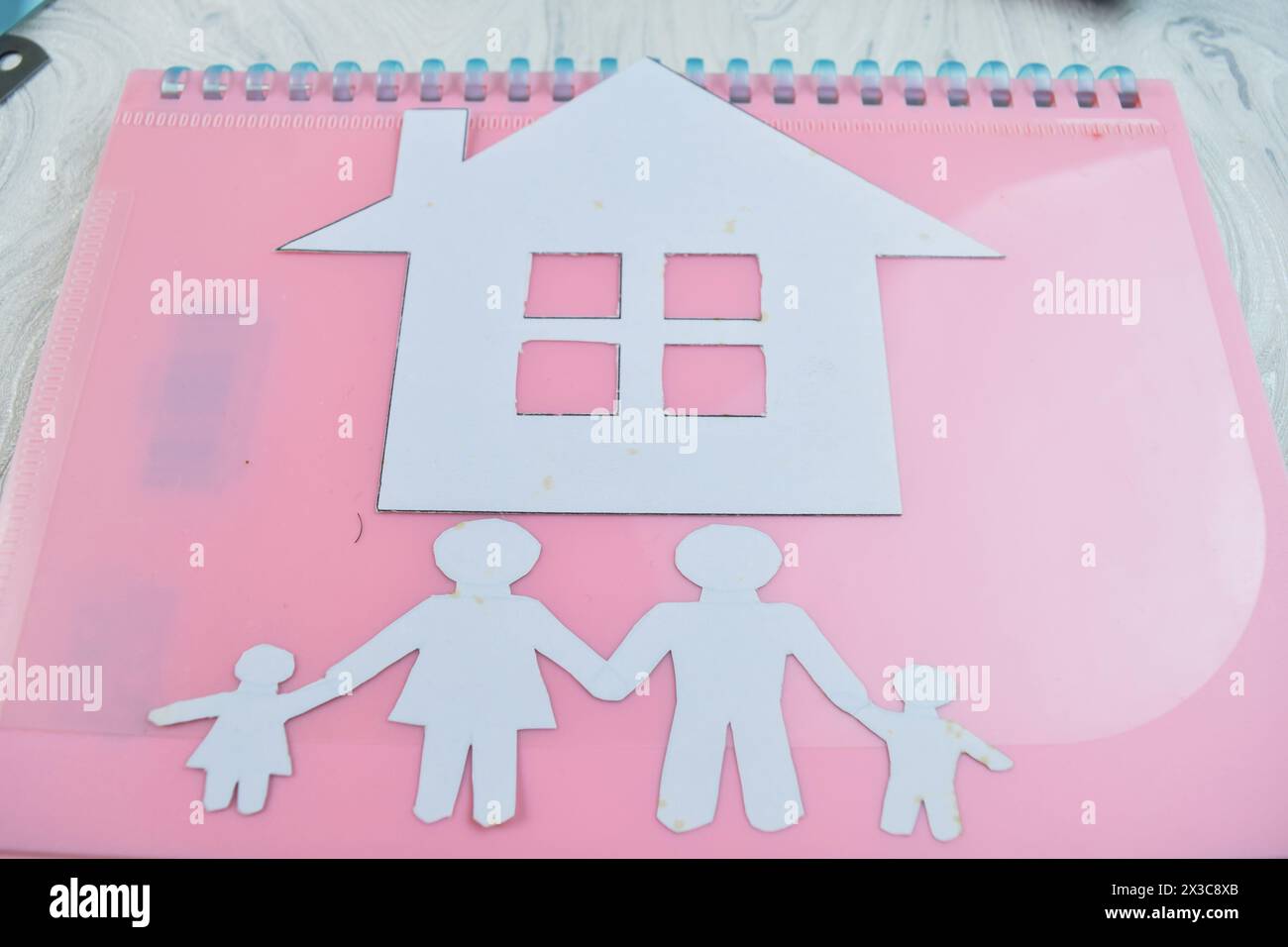 Maison faite de paperasse avec des figures de famille sur fond de bois métaphore pour le rêve de la propriété Banque D'Images