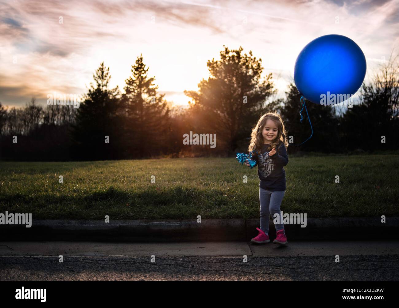 Petite fille heureuse tenant un grand ballon bleu à l'extérieur Banque D'Images