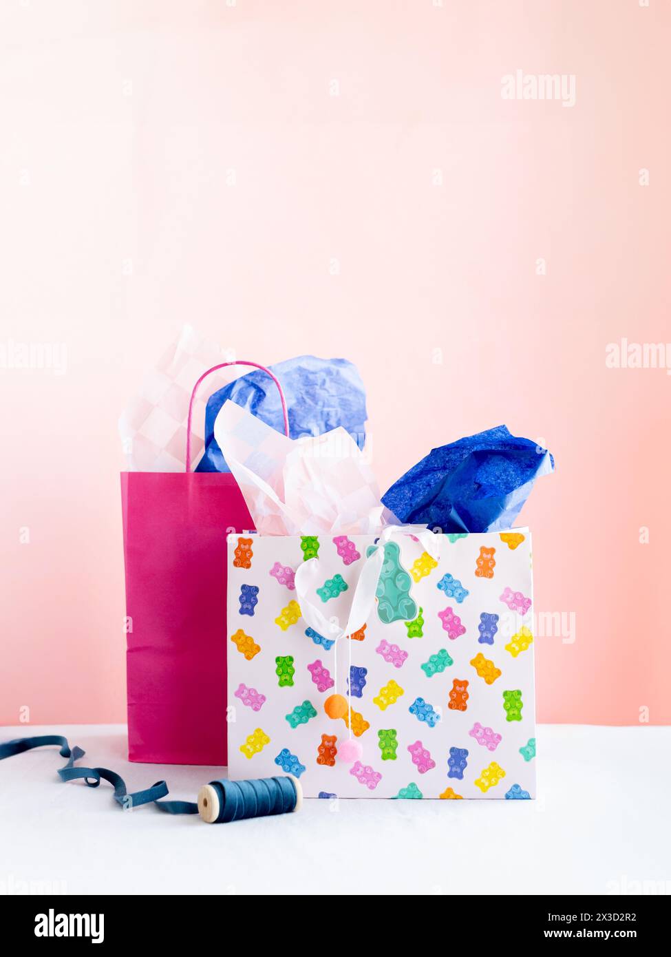 Sacs cadeaux vibrants et papier de soie sur rose Banque D'Images