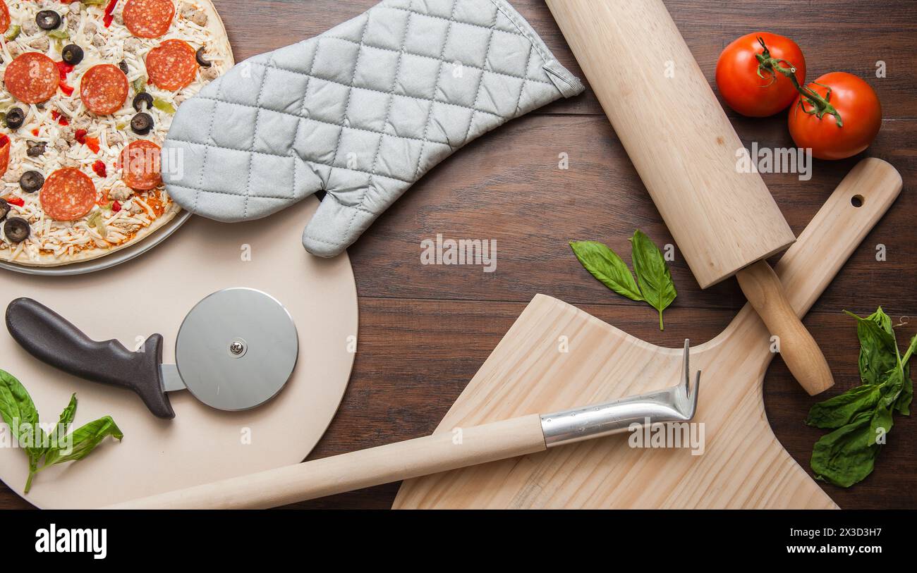 Pizza prête à cuire avec basilic frais et ustensiles de cuisine Banque D'Images