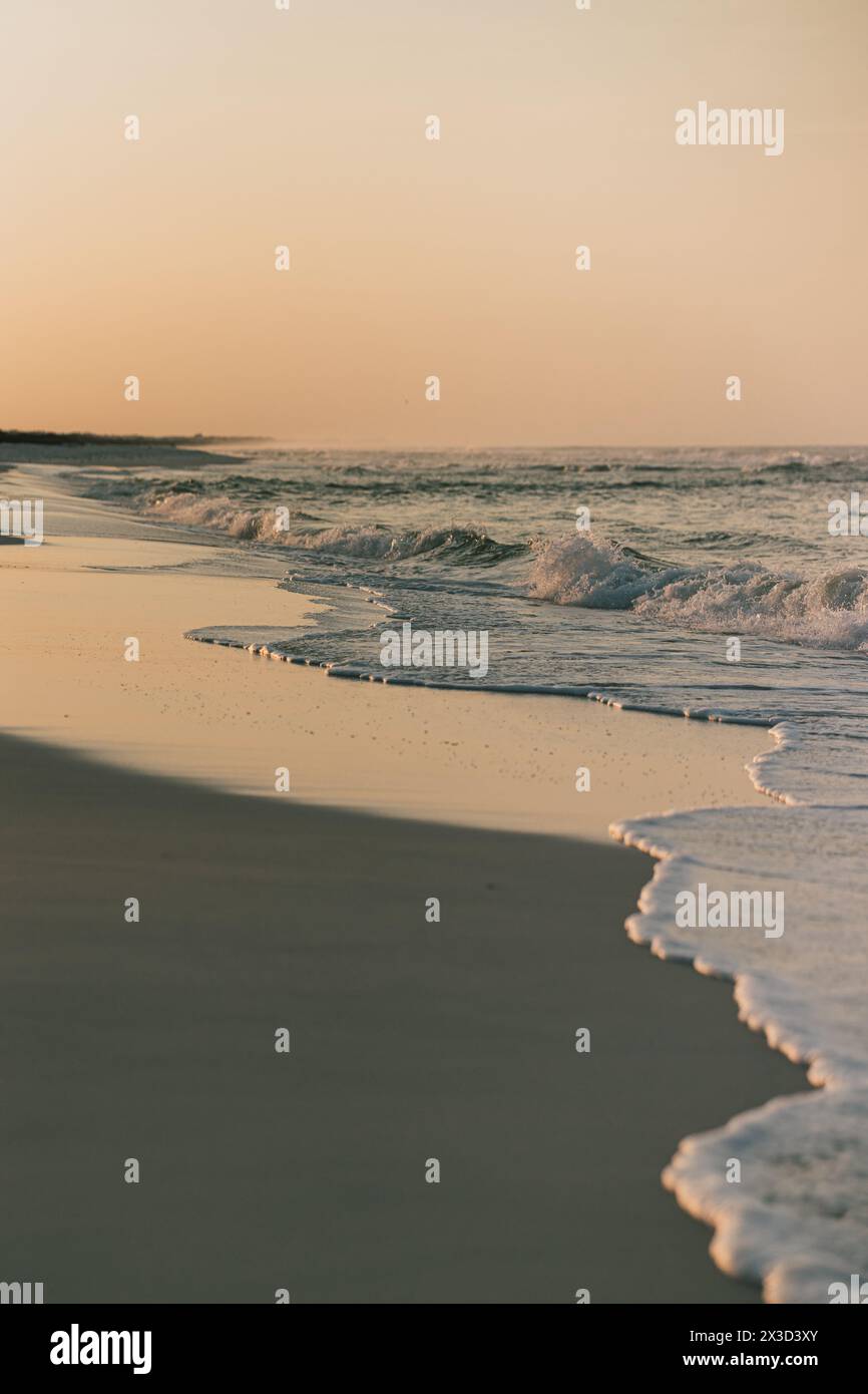 Vagues douces à un lever de soleil tranquille sur la plage Banque D'Images