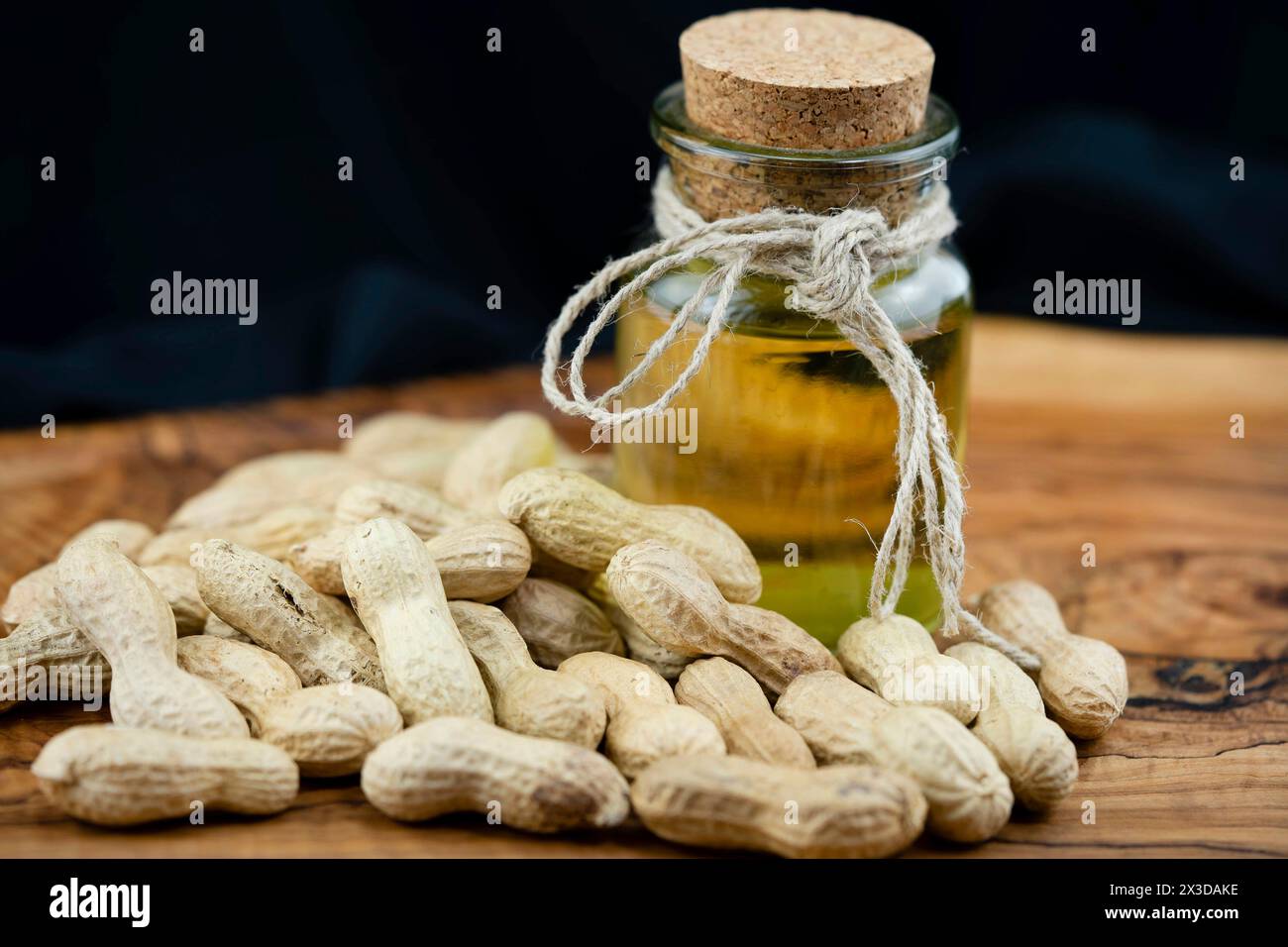 Arachide, arachide (Arachis hypogaea), arachides non pelées avec une bouteille d'huile, ingrédients pour le beurre d'arachide Banque D'Images