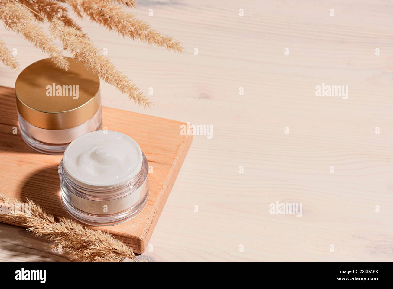 Pots de crème cosmétique avec de l'herbe de pampas sur fond beige pastel, espace de copie. Produits de beauté nourrissants, crème anti-âge riche. Banque D'Images
