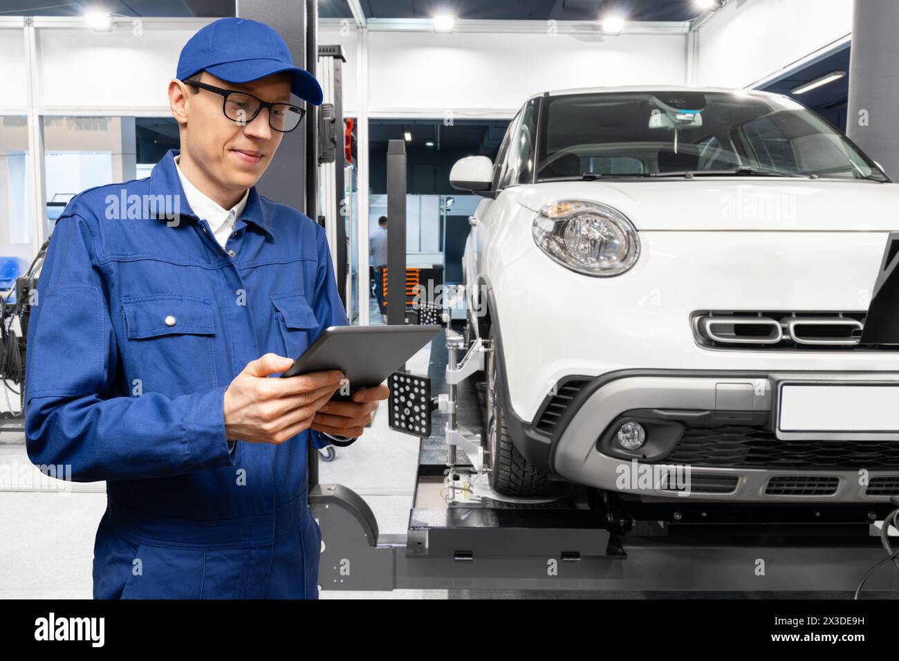 Technicien de service avec tablette numérique sur le fond de la voiture dans le service de voiture Banque D'Images