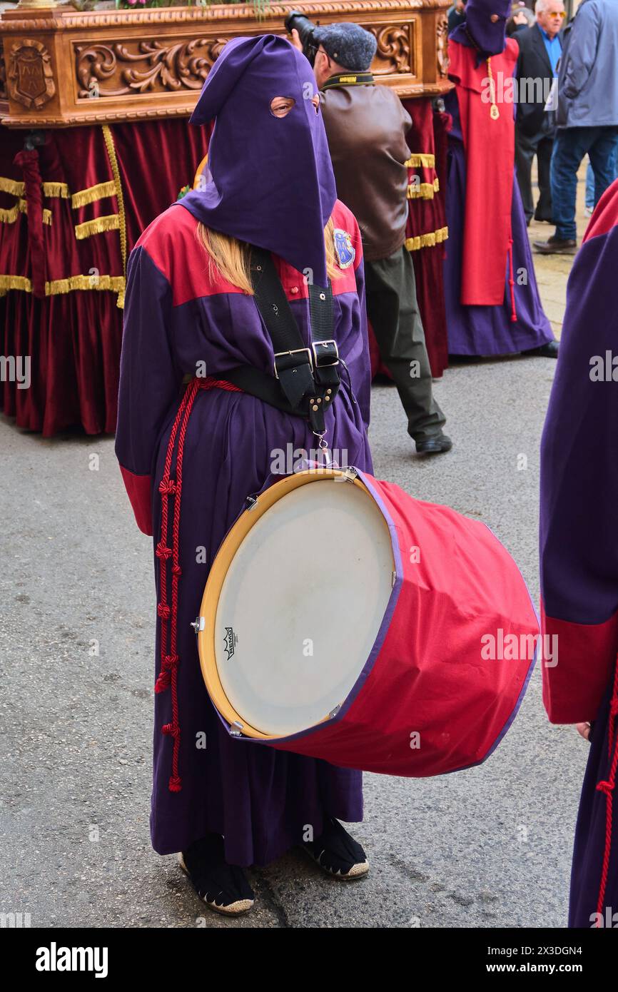 Tarragone, Espagne - 26 avril 2024 : image d'un batteur vêtu d'une robe violette et d'une cagoule participant à une procession religieuse jouant un rouge et blanc Banque D'Images