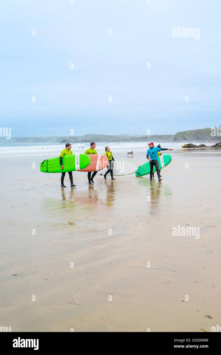 Un instructeur de surf de l'Escape Surf School marchant avec un groupe de surfeurs débutants sur la plage de Towan à Newquay en Cornouailles au Royaume-Uni. Banque D'Images
