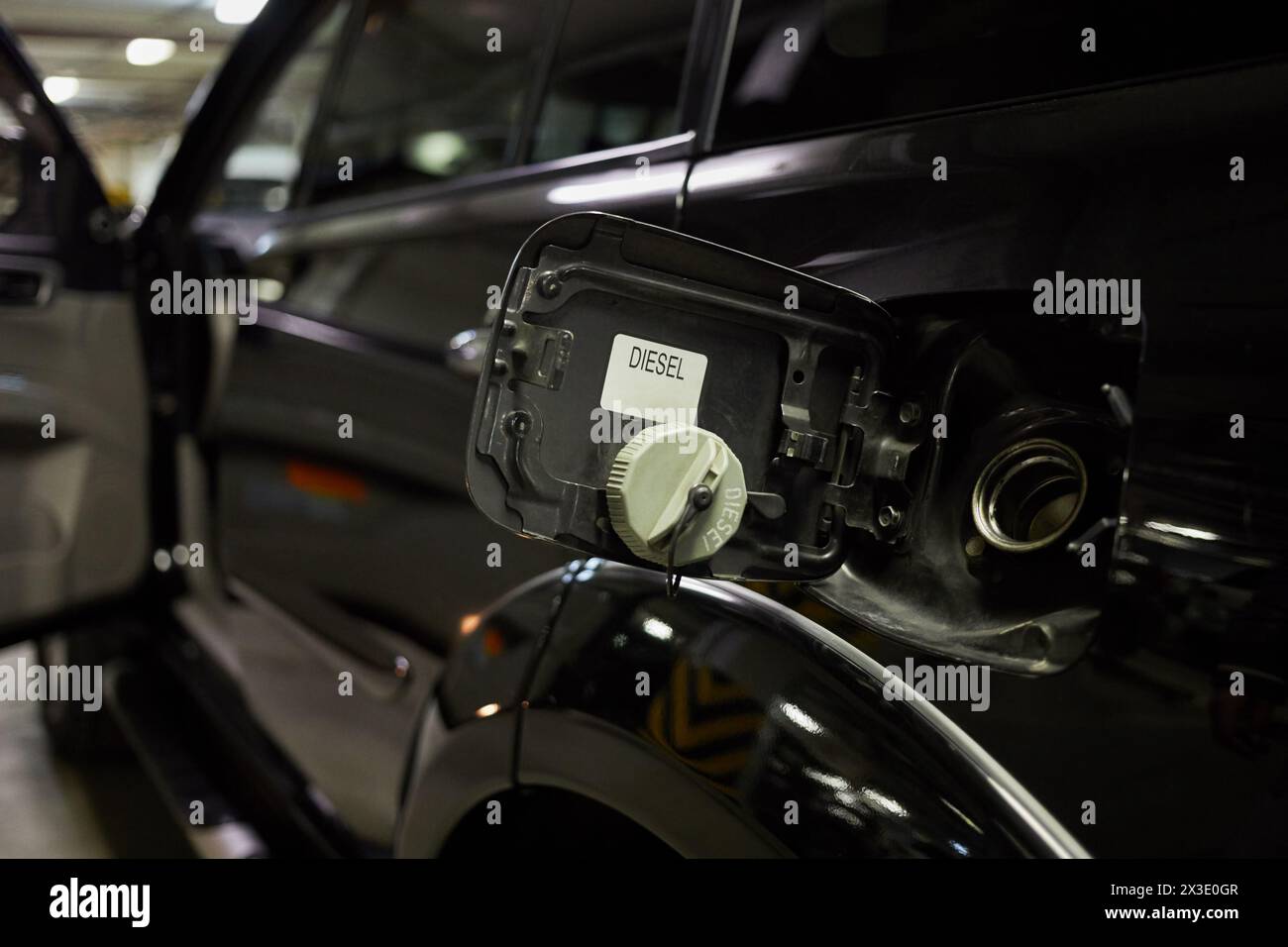 Bouchon de carburant ouvert d'une voiture noire dans un parking souterrain. Banque D'Images