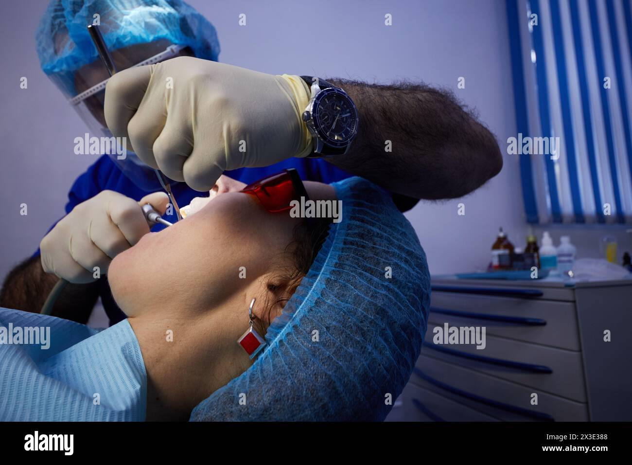 Tête de patient en profil sur chaise de dentiste et mains de médecin avec des instruments dentaires. Banque D'Images