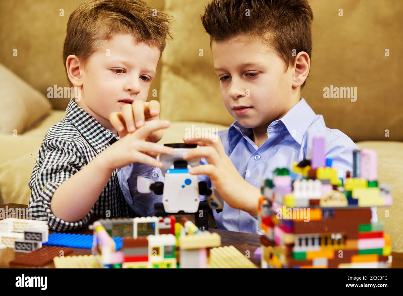 Deux garçons jouent avec des enfants construisant un kit de briques en plastique dans la chambre. Banque D'Images