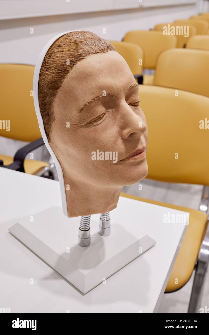 Masque en plastique imitant le visage d'une femme âgée, attaché par deux ressorts pour se tenir debout sur la table. Banque D'Images